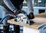 Ein Arbeiter mit Sicherheitsausrüstung schneidet Spanplatten mit einer Kreissäge.