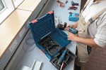 Eine Person mit Schutzausrüstung bereitet an einem Arbeitsplatz eine Akkubohrmaschine vor.
